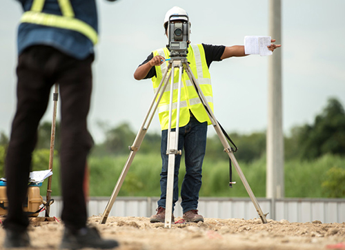 two people in yellow traffic vests performing a survey